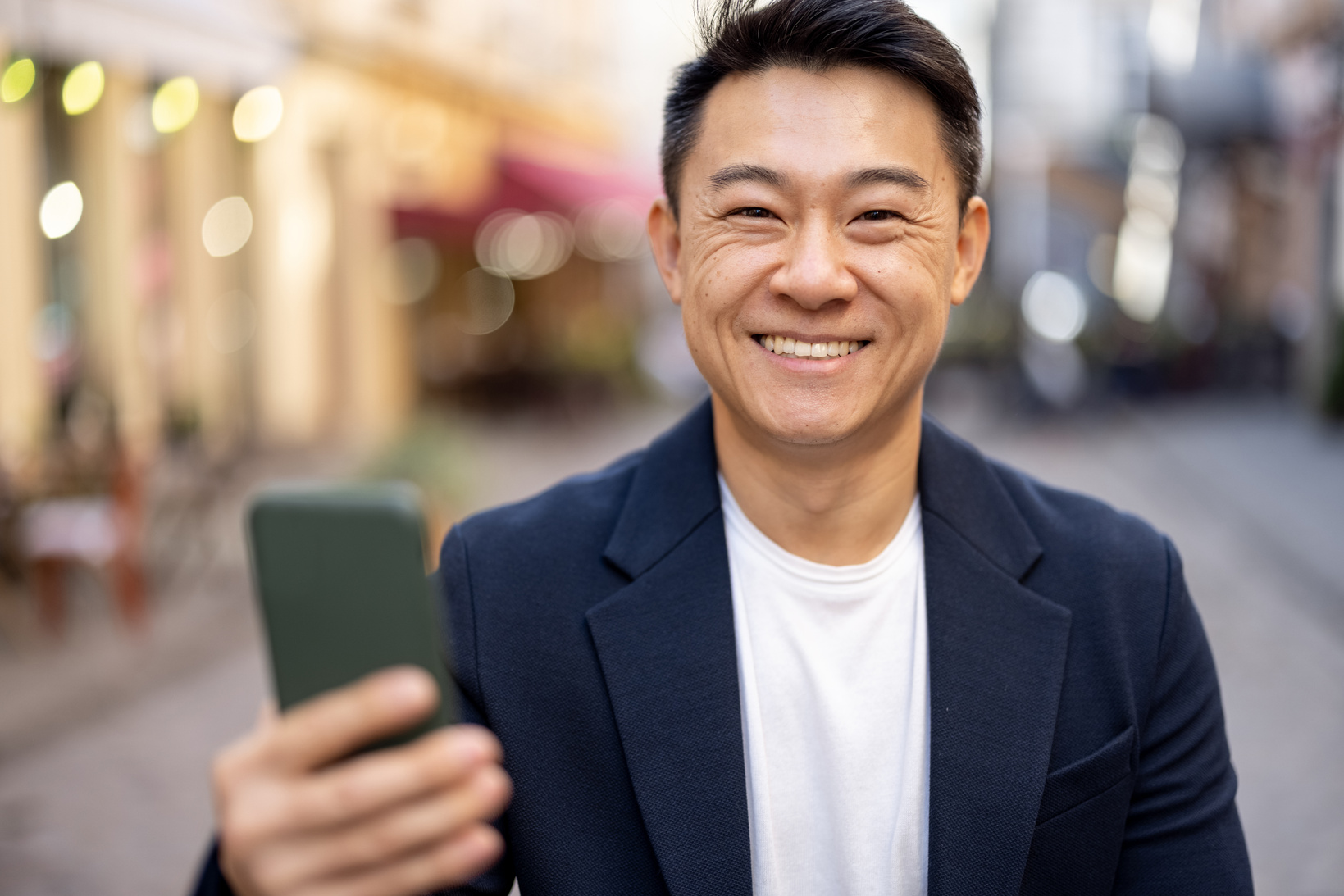 Asian Man Holding Smartphone and Looking at Camera